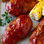 Smoked chicken breasts on a sheet pan with corn on the corn and fresh herbs.