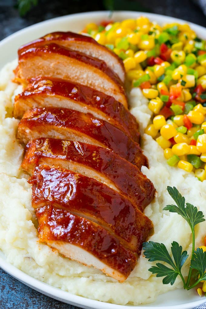 Sliced smoked chicken breast over mashed potatoes and corn.