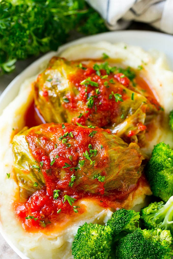 Stuffed cabbage rolls served over mashed potatoes with a side of broccoli.