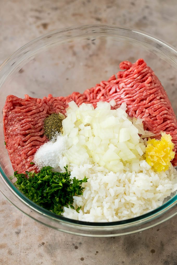 Ground beef, onion garlic, rice and herbs in a mixing bowl.