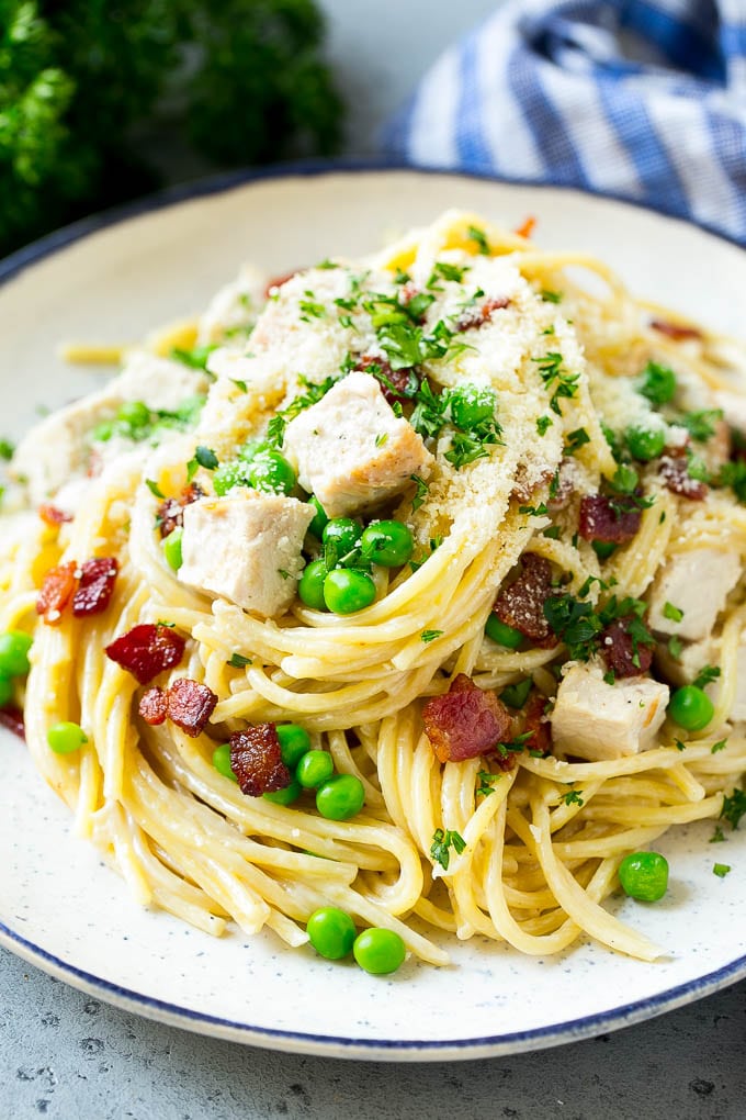 A plate of turkey pasta carbonara topped with cubes of turkey, parsley and parmesan cheese.