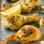 Baked chicken drumsticks flavored with garlic and herbs, then garnished with lemon wedges and parsley.