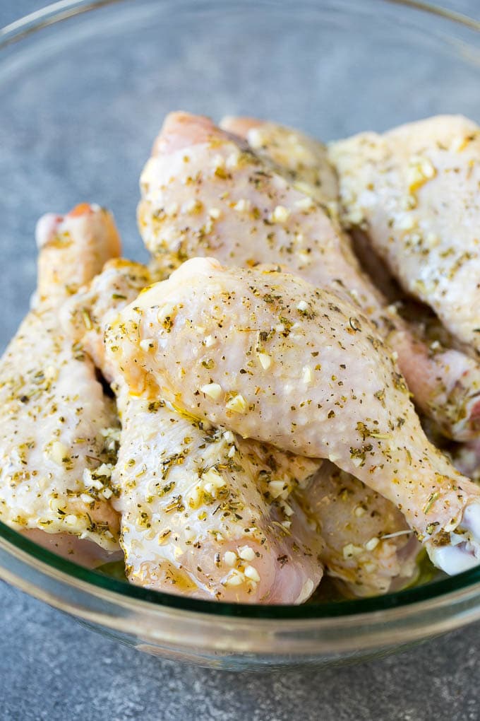 A bowl of chicken drumsticks in a garlic and herb marinade.