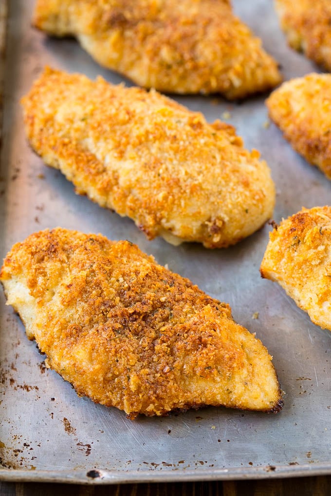 Baked crispy chicken breasts on a baking sheet pan.