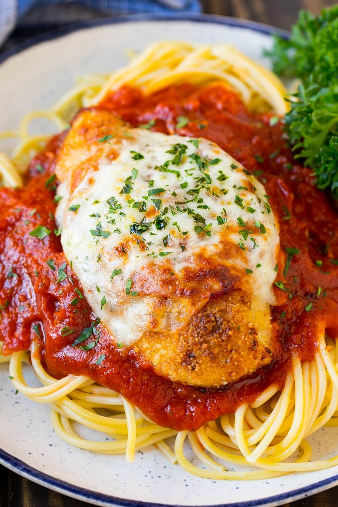 Baked chicken parmesan served over spaghetti with tomato sauce.