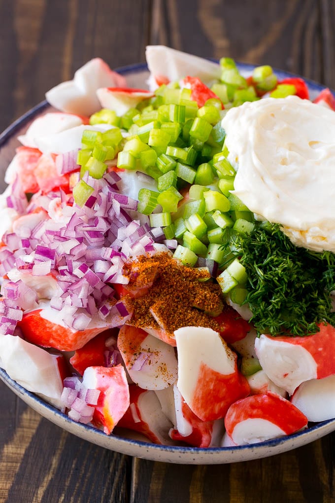 Imitation crab, seasoning, dill, celery and mayonnaise in a bowl.