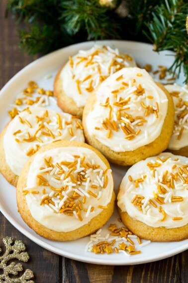 Eggnog cookies topped with frosting and gold sprinkles on a serving plate.