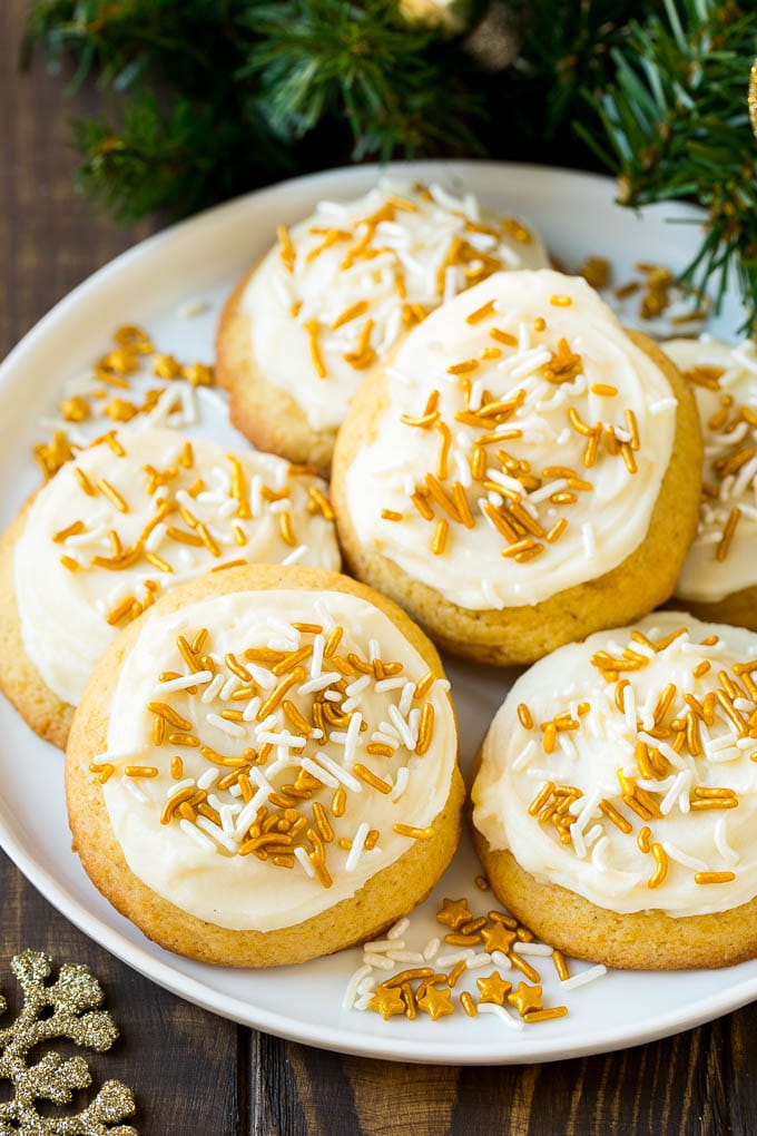 Eggnog Cookies Recipe | Holiday Cookies | Christmas Cookies #cookies #eggnog #baking #christmas #sprinkles #dessert #dinneratthezoo Eggnog cookies topped with frosting and gold sprinkles on a serving plate.