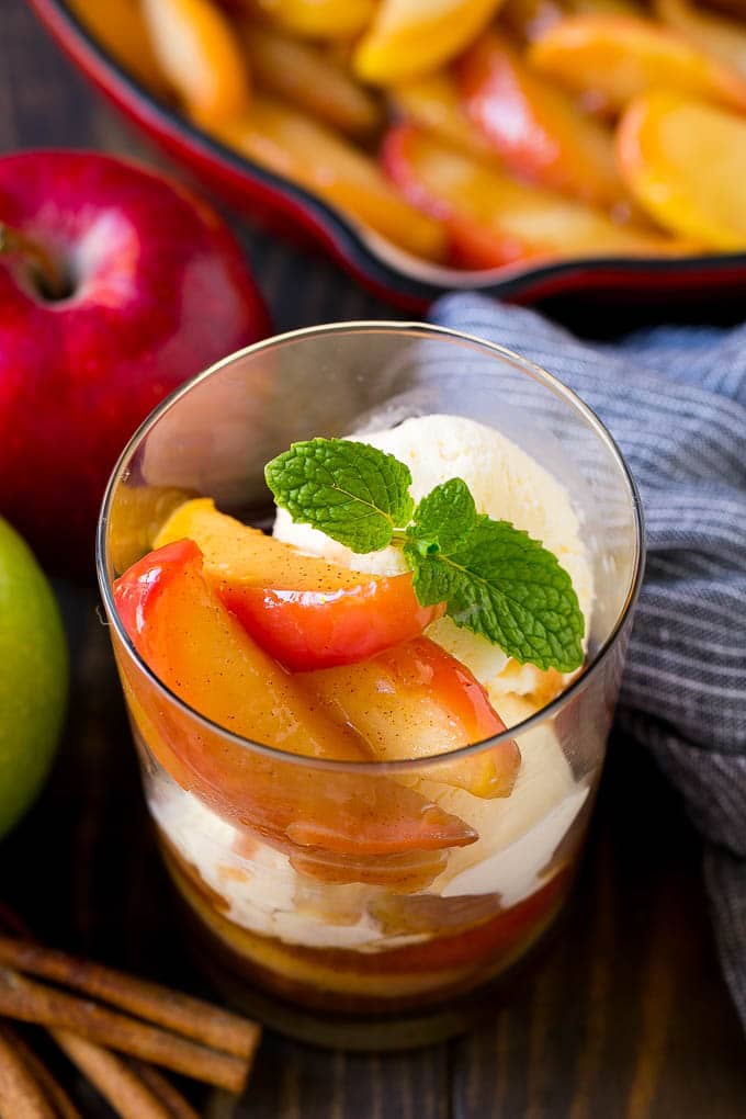 A cup of fried apples served with vanilla ice cream and garnished with fresh mint.