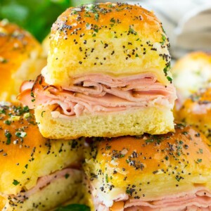 Ham and cheese sliders on a serving plate, garnished with parsley.