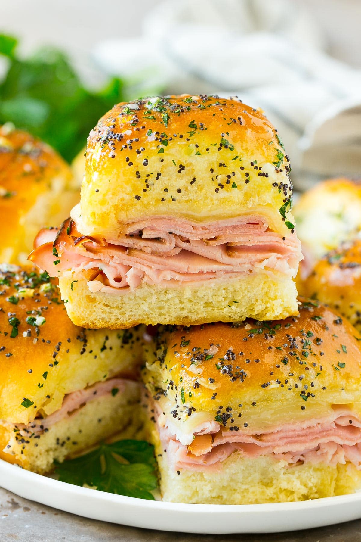 Ham and cheese sliders on a serving plate, garnished with parsley.