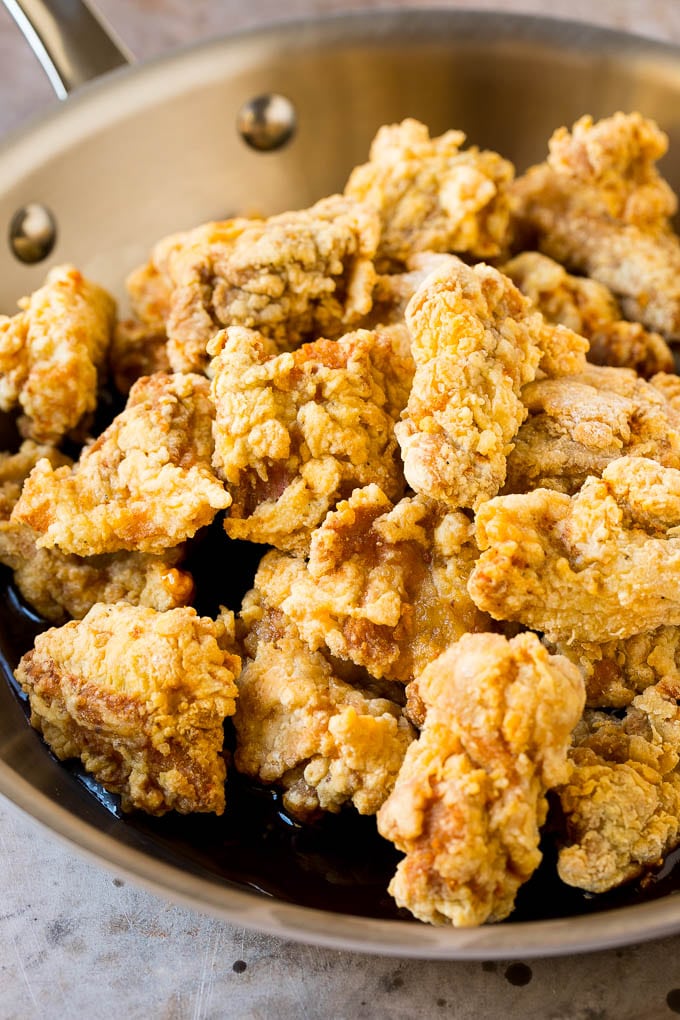 Fried chicken thigh pieces in a pan of sweet and savory Korean sauce.