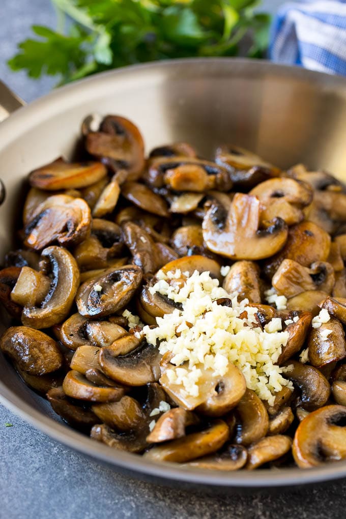 Cooked mushrooms and minced fresh garlic in a frying pan.