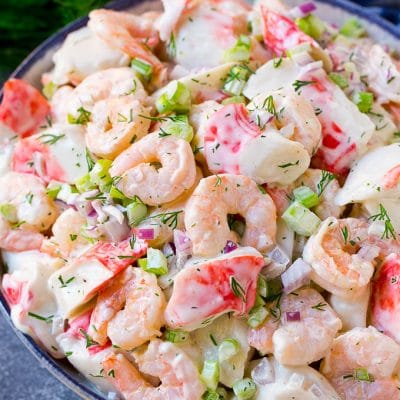 A serving bowl of seafood salad made with shrimp and imitation crab in a creamy dill dressing.