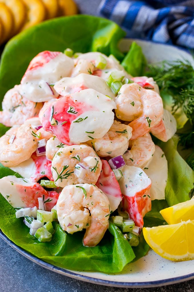 A lettuce leaf topped with seafood salad with crackers on the side.