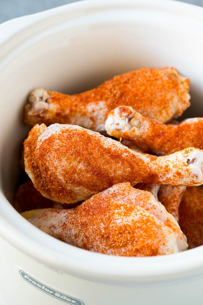Chicken drumsticks in a slow cooker coated in BBQ spice rub.