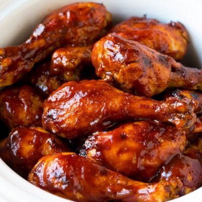 Slow cooker chicken drumsticks coated in BBQ sauce inside a crock pot.