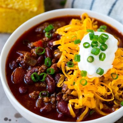 A bowl of slow cooker chili topped with shredded cheese, sour cream and green onions.