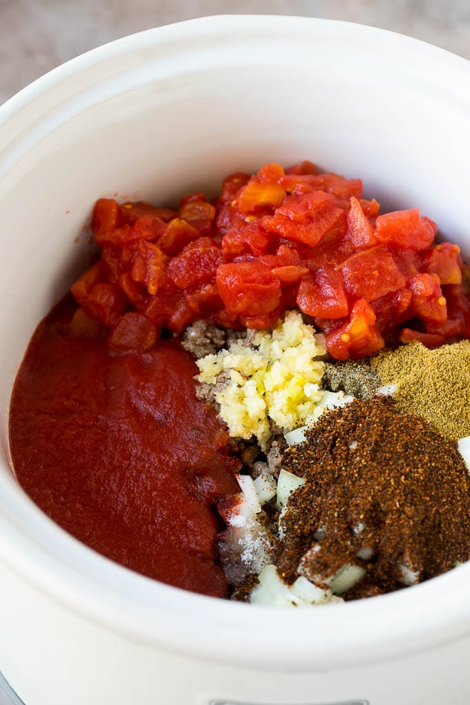 Ground beef, spices, garlic and tomatoes in a slow cooker.