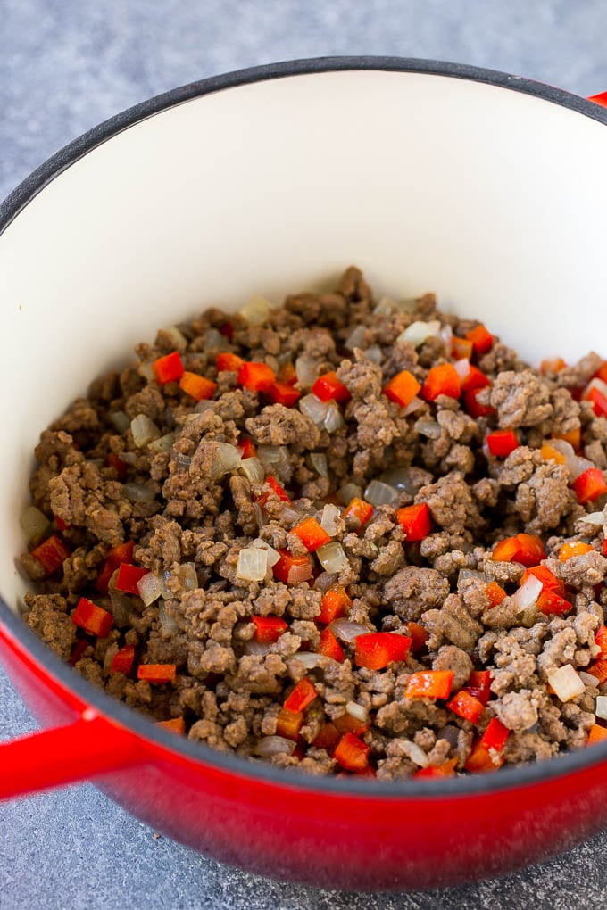 Cooked ground beef with onions and bell peppers in a pot.