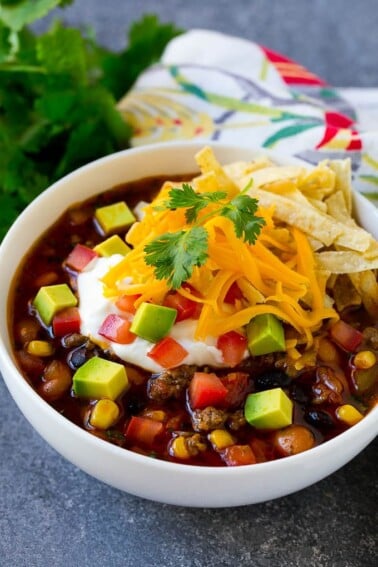 A bowl of taco soup topped with tortilla strips, sour cream, cheese and avocado.