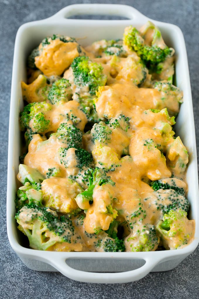 Broccoli florets in a baking dish coated with cheese sauce.