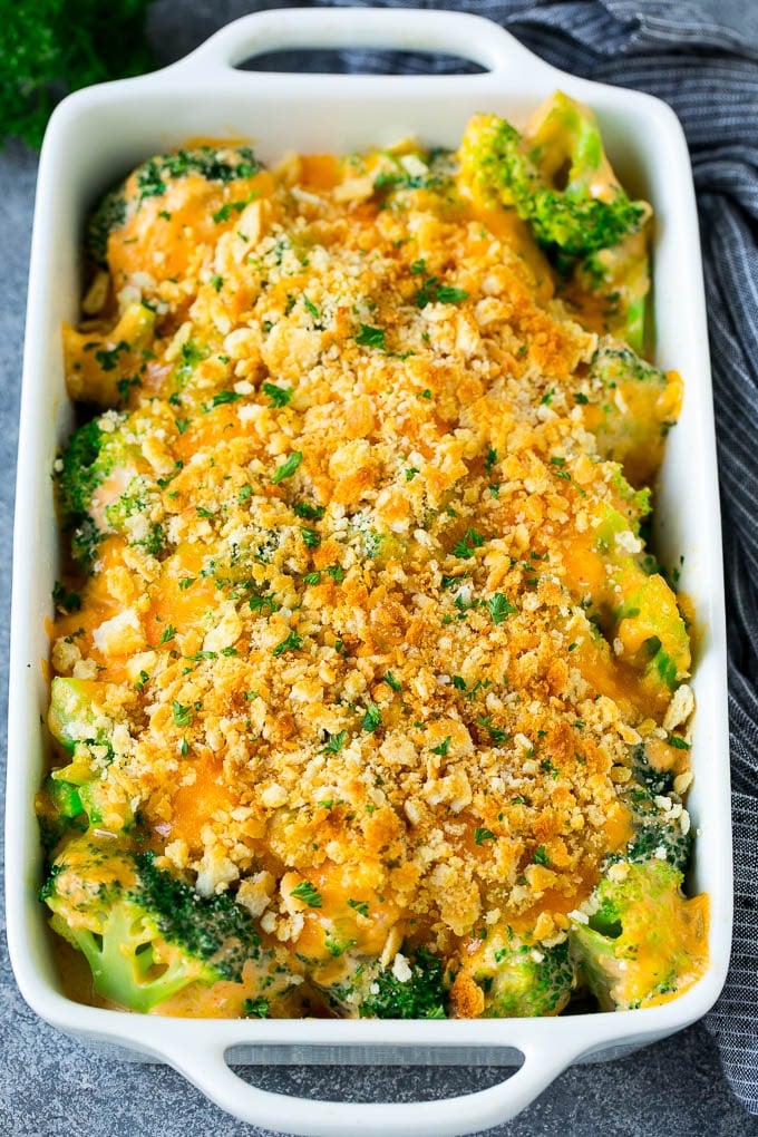 A pan of broccoli casserole topped with crackers, melted cheese and parsley.