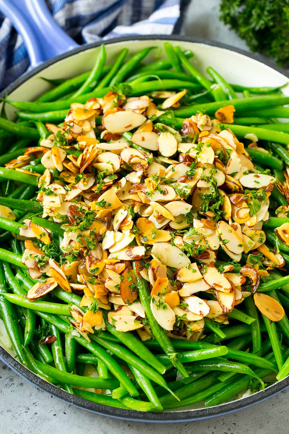 A pan of green beans almondine with parsley on top.