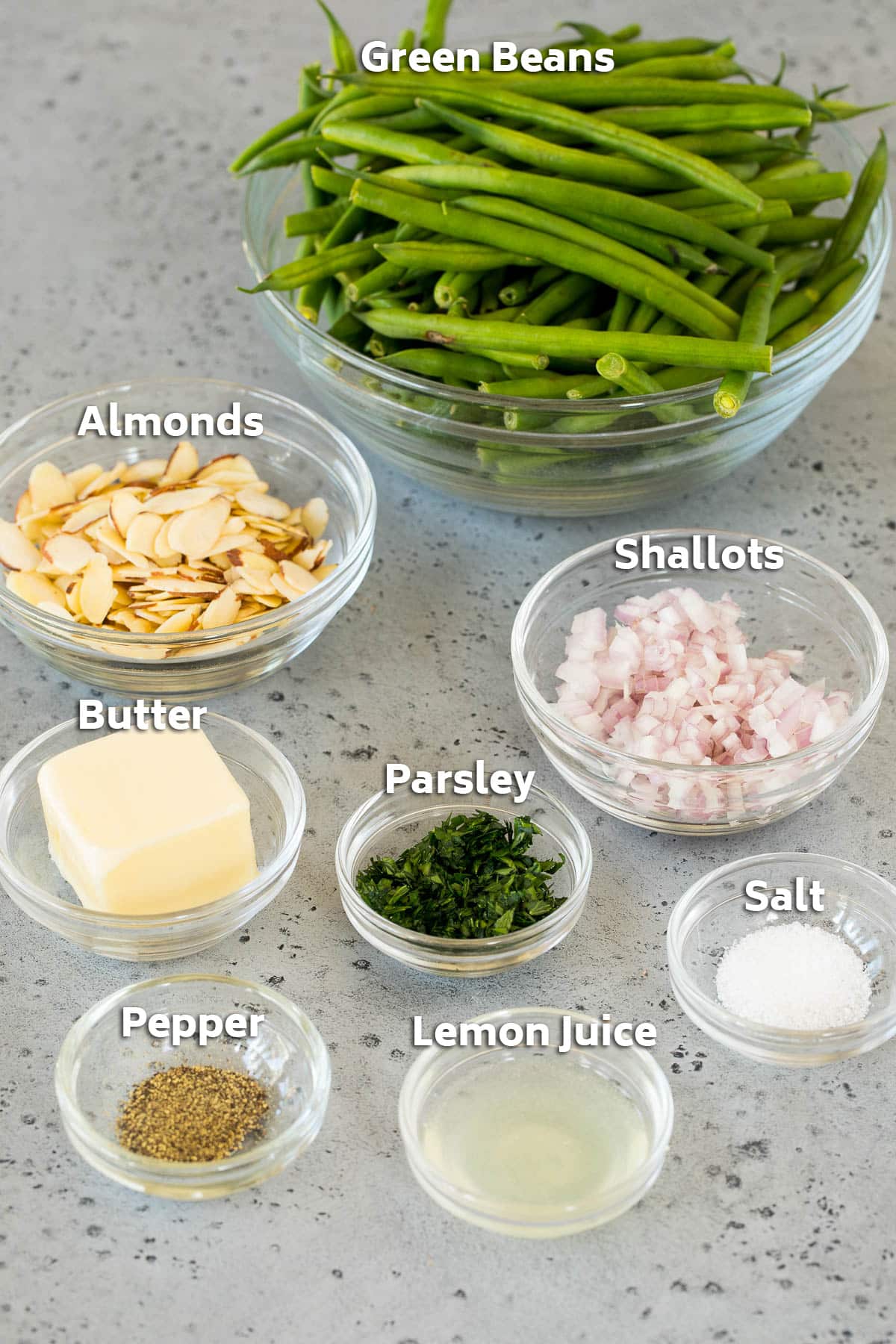 Bowls of ingredients including green beans, butter, shallots, almonds and seasoning.