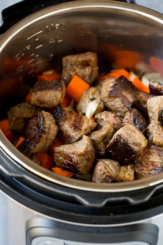 Browned stew meat and vegetables inside an Instant Pot.