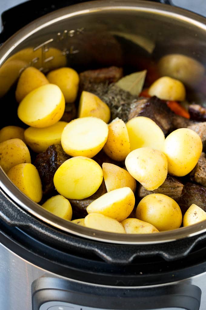 Meat, vegetables and halved baby potatoes in a pressure cooker.