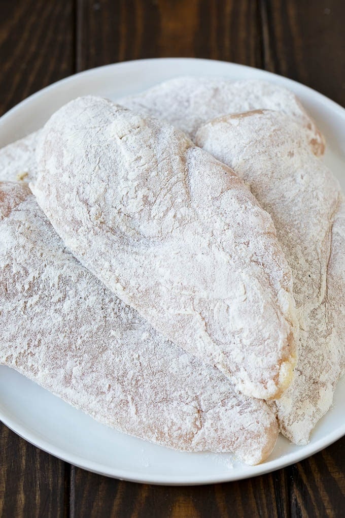 Chicken breasts coated in flour and seasonings.