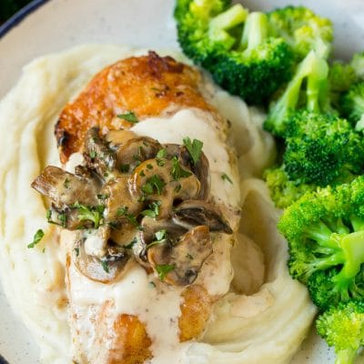 Instant Pot chicken with creamy mushroom sauce served over mashed potatoes with a side of broccoli.