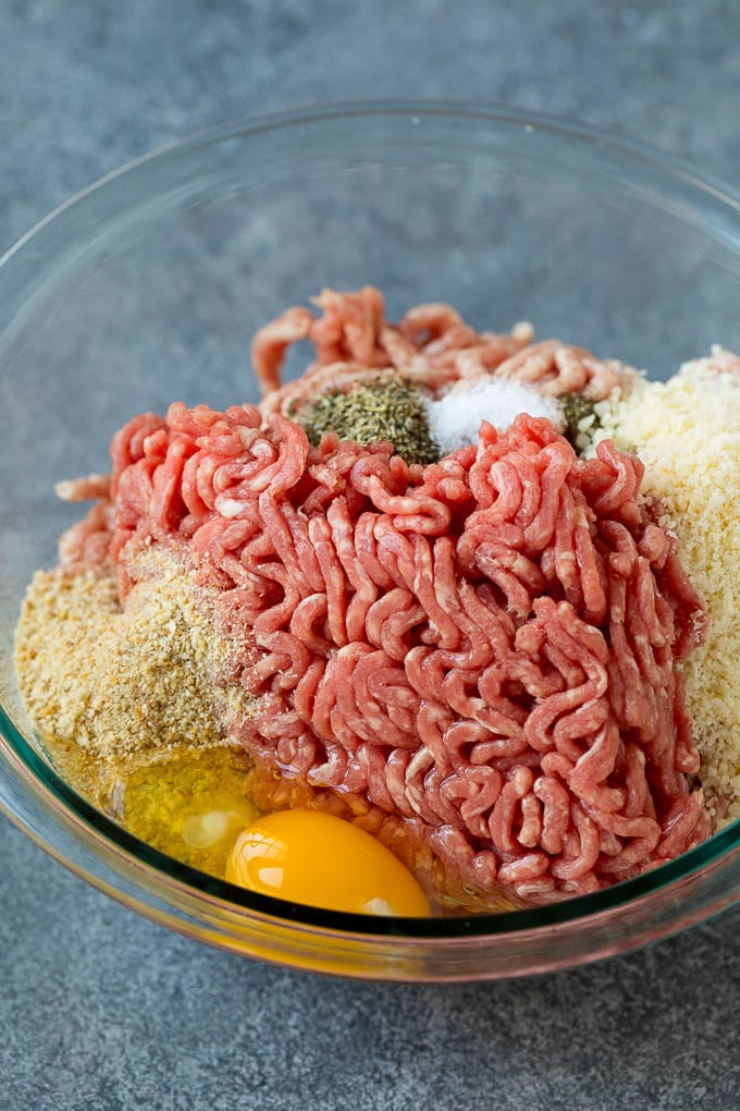 Ground beef, pork, breadcrumbs, parmesan cheese and herbs in a mixing bowl.