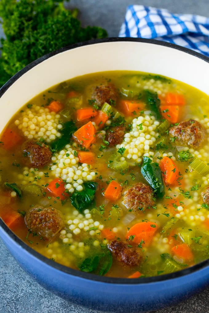 A pot of Italian wedding soup filled with meatballs, vegetables and pasta in a savory broth.