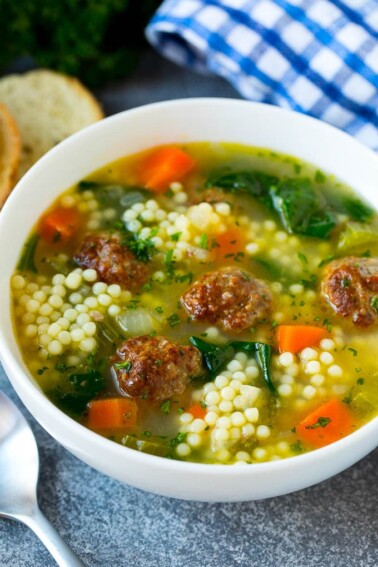 A bowl of Italian wedding soup with meatballs, carrots, spinach and pasta.