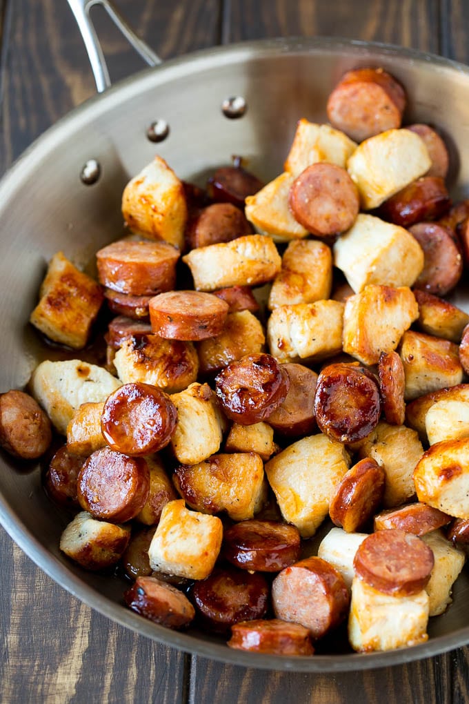 A pan full of sauteed chicken pieces and andouille sausage.