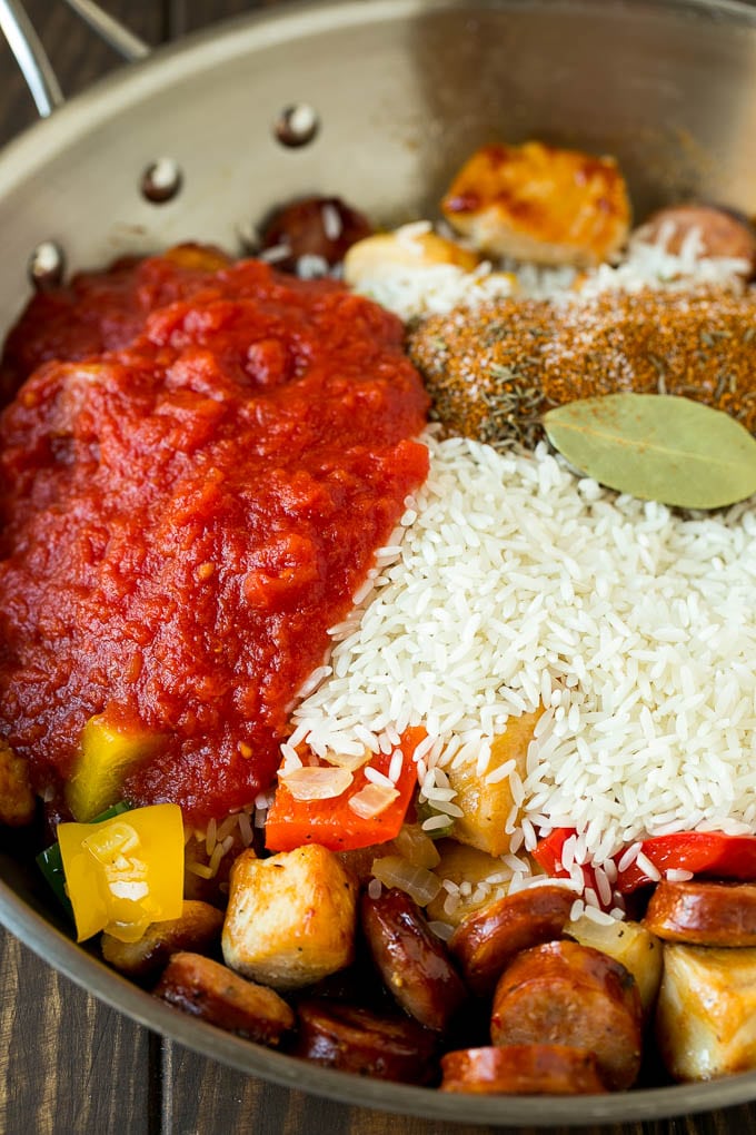 Vegetables, chicken, sausage, rice and tomatoes in a pan.