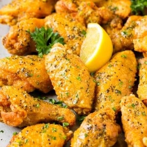 A tray of lemon pepper wings garnished with parsley and lemon.