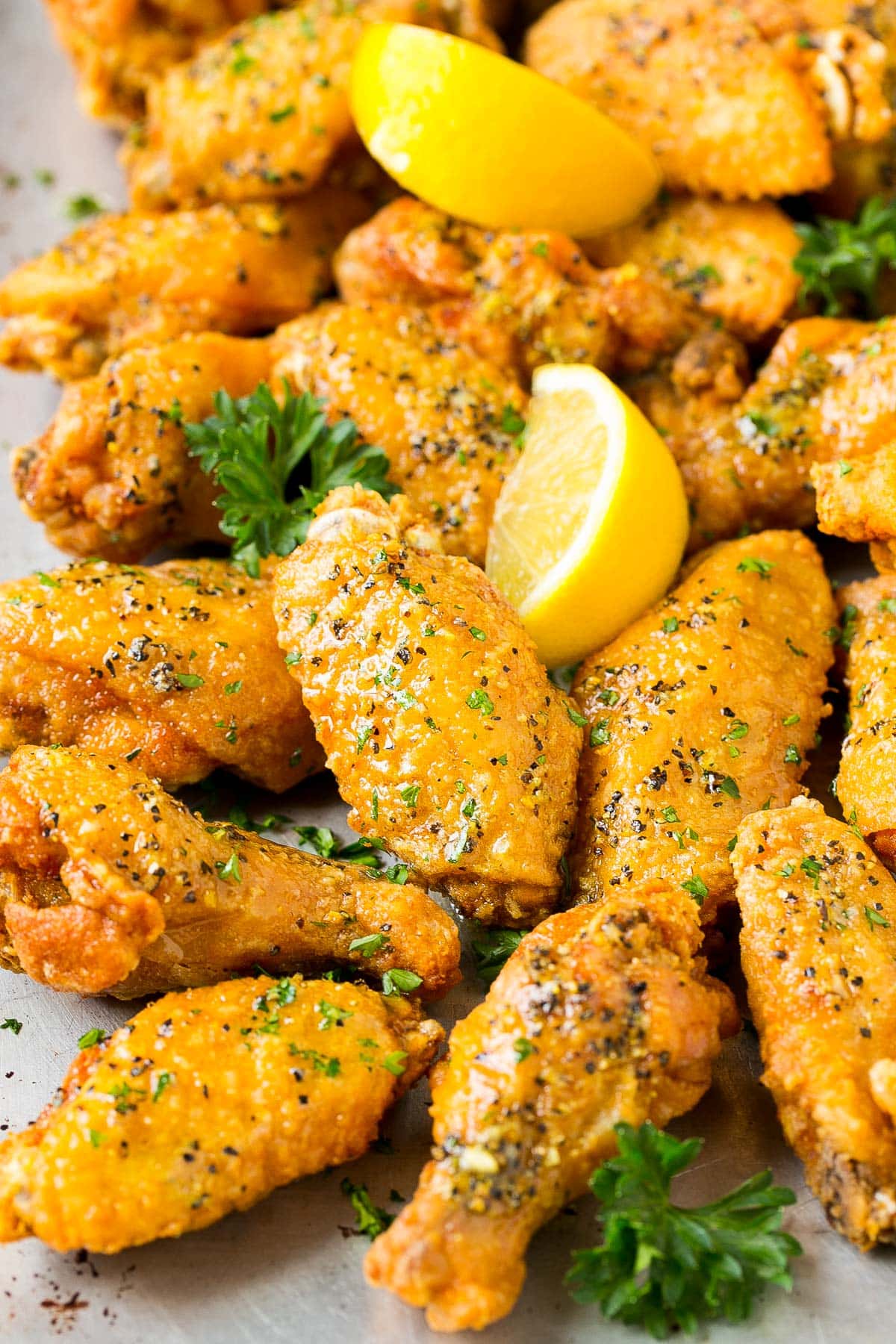 A tray of lemon pepper wings garnished with parsley and lemon.