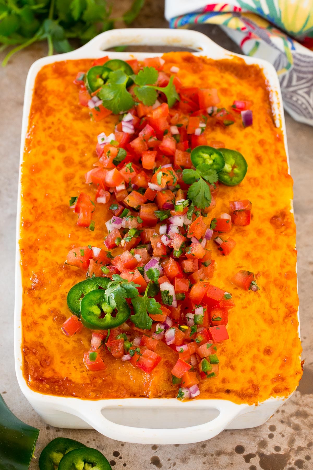 A baking dish filled with Mexican casserole, topped with fresh salsa.