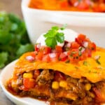 A plate of Mexican casserole with layers of meat, tortillas and cheese.