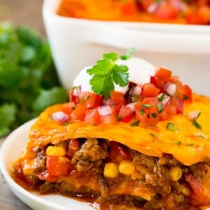 A plate of Mexican casserole with layers of meat, tortillas and cheese.