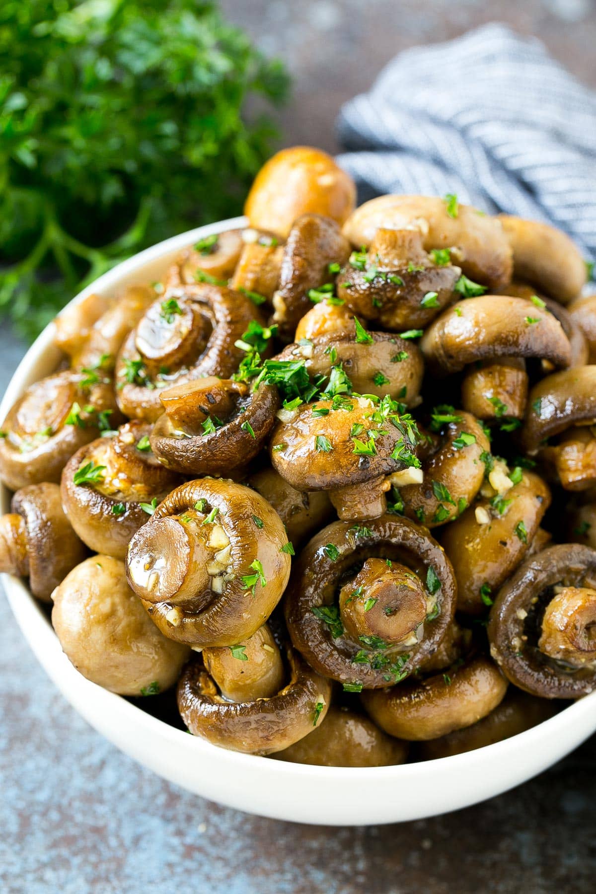 A bowl of roasted mushrooms topped with fresh parsley.