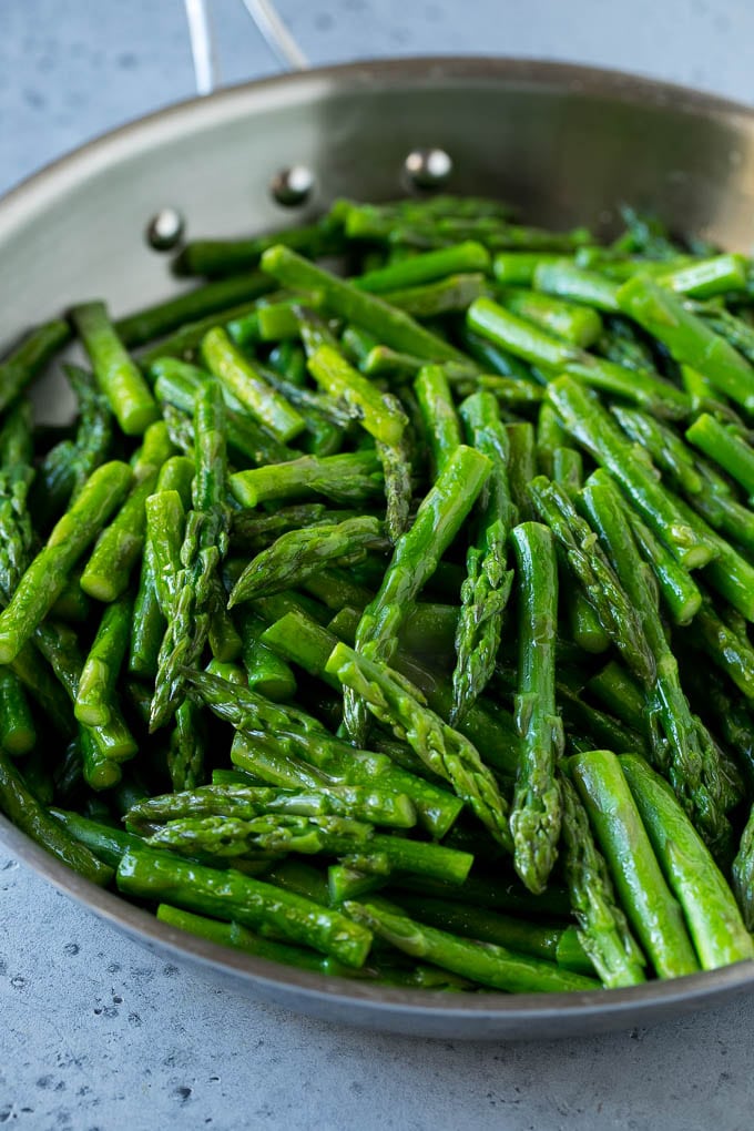 Cooked chopped asparagus stalks in a stainless steel pan.