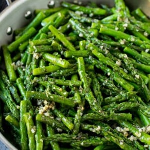 Sauteed asparagus with butter, garlic and herbs in a skillet.