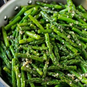 Sauteed asparagus with butter, garlic and herbs in a skillet.