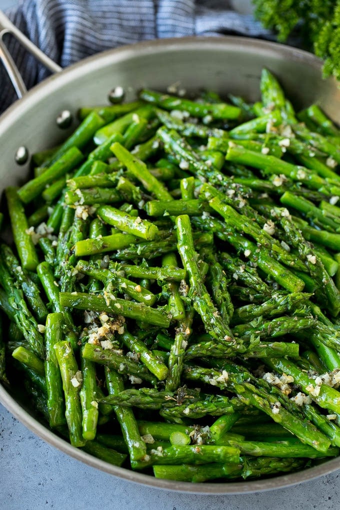 Sauteed asparagus with butter, garlic and herbs in a skillet.