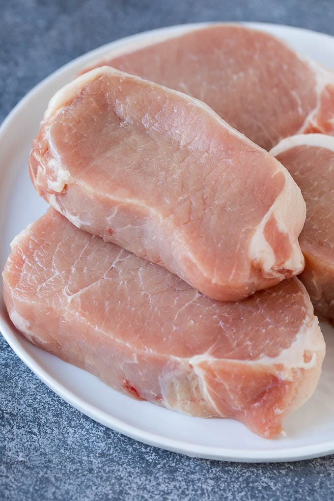Uncooked boneless pork chops on a plate.