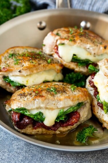 Stuffed pork chops filled with sun dried tomatoes, spinach and cheese in a skillet.
